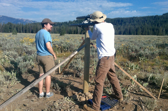 Joe and Daniel affixing hardware that will hold solar panel to post. *Note: wooden stakes had been used to prop up pole while cement dried.*